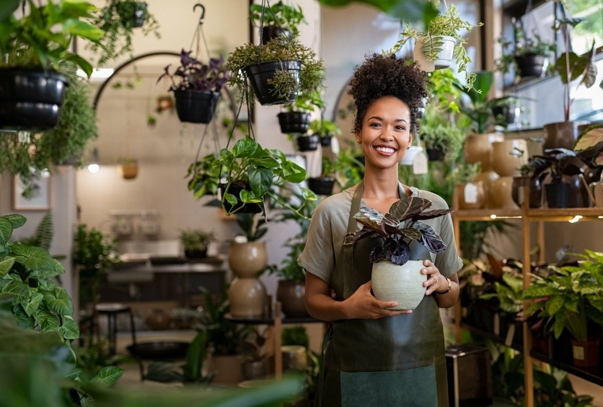 A South African small-business owner in her plant shop, holding a potted plant